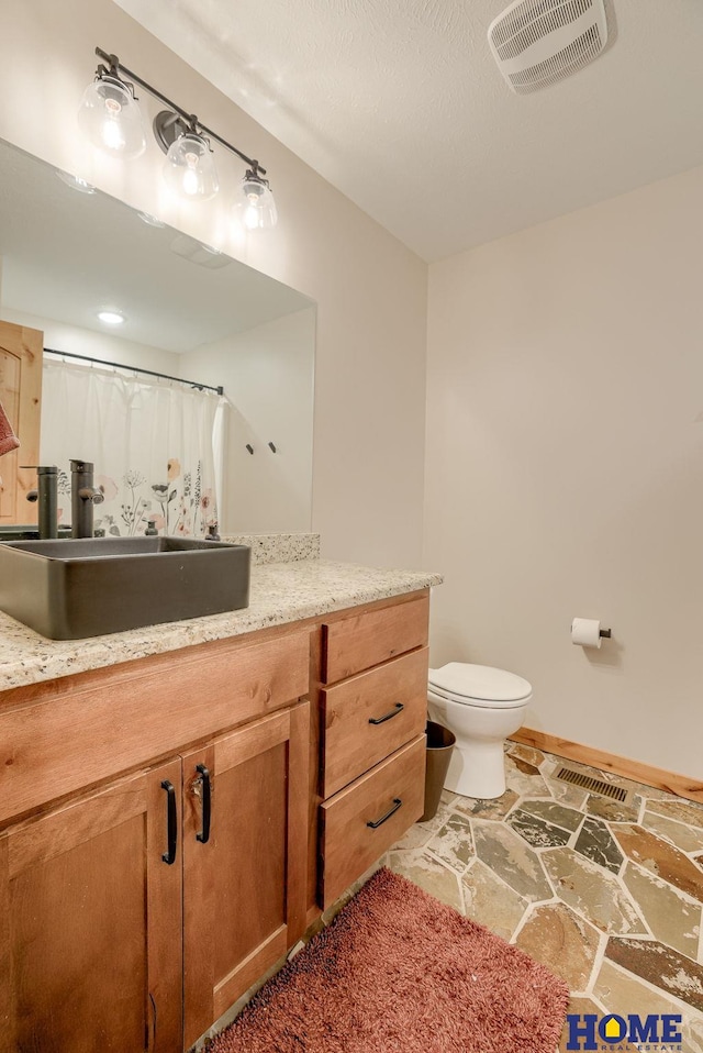 bathroom with vanity, curtained shower, and toilet