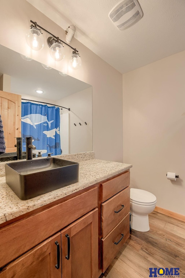 bathroom with a shower with curtain, toilet, vanity, and hardwood / wood-style flooring