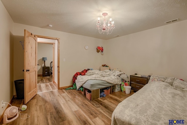 bedroom featuring wood-type flooring, a textured ceiling, and an inviting chandelier