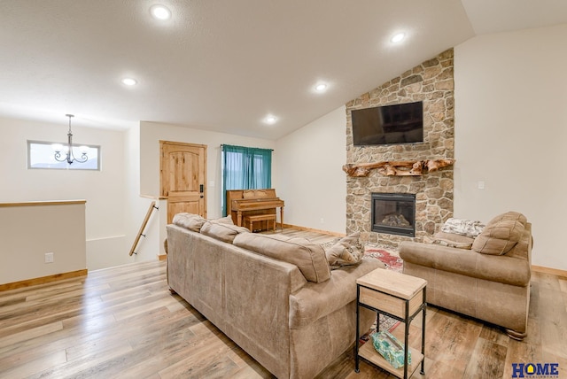 living room with a stone fireplace, light hardwood / wood-style flooring, and vaulted ceiling