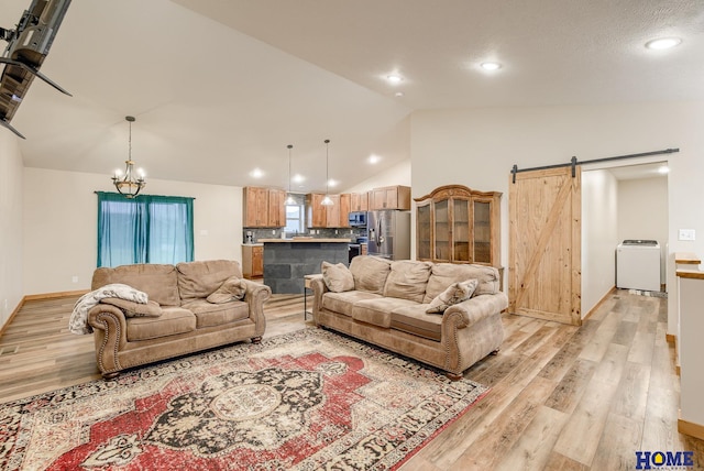 living room featuring a chandelier, a barn door, high vaulted ceiling, and light hardwood / wood-style flooring