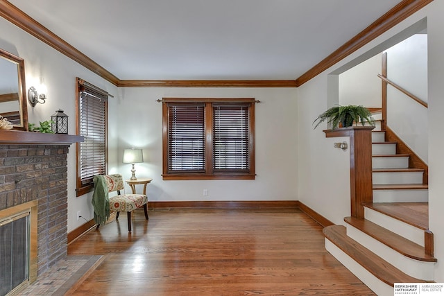 sitting room featuring wood-type flooring, a brick fireplace, and ornamental molding