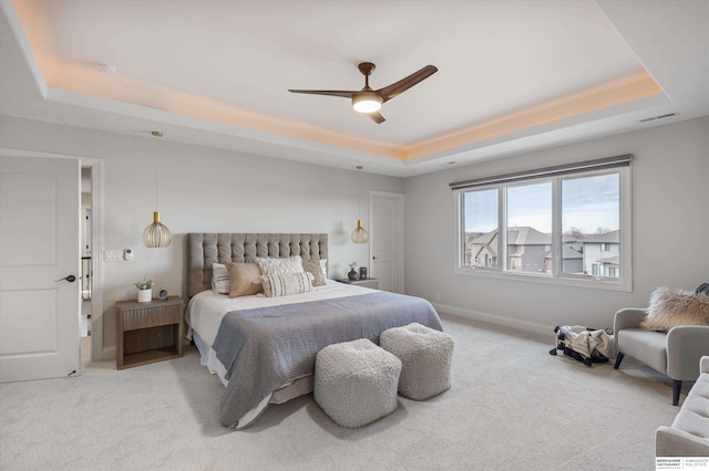 carpeted bedroom with ceiling fan and a tray ceiling