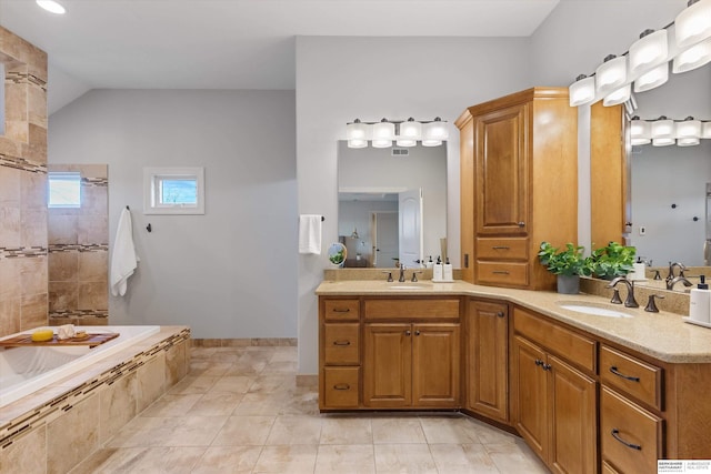 bathroom featuring vanity, tile patterned floors, and a relaxing tiled tub