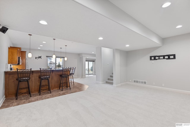 kitchen featuring light carpet, a breakfast bar, and pendant lighting