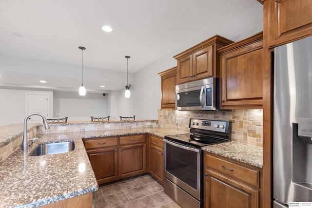 kitchen featuring stainless steel appliances, hanging light fixtures, kitchen peninsula, light stone counters, and sink