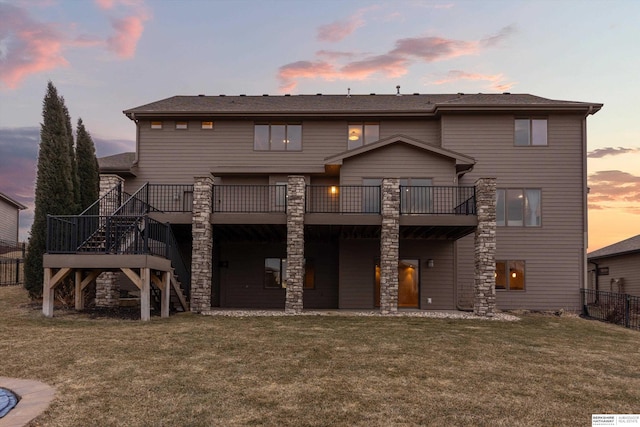 back house at dusk with a lawn and a wooden deck