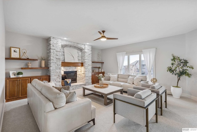 living room featuring a fireplace, light carpet, and ceiling fan