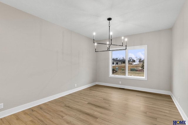 unfurnished dining area with light hardwood / wood-style floors and an inviting chandelier