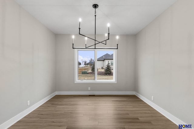 unfurnished dining area with hardwood / wood-style floors and a chandelier