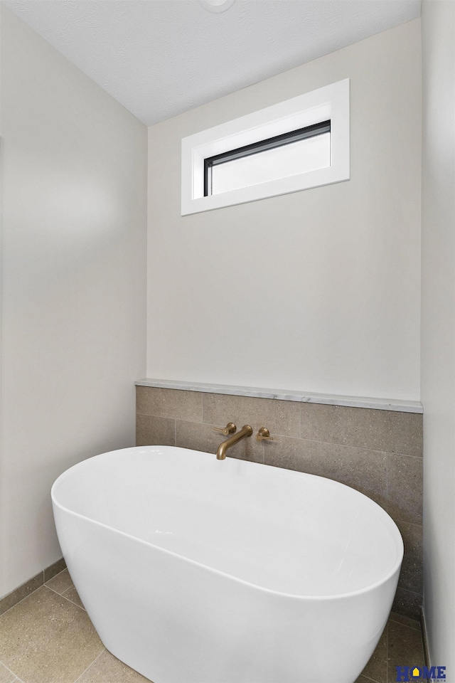 bathroom with a washtub and tile patterned flooring