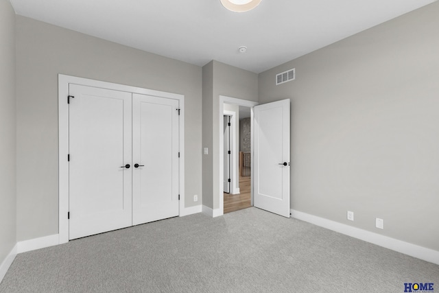 unfurnished bedroom with light colored carpet and a closet