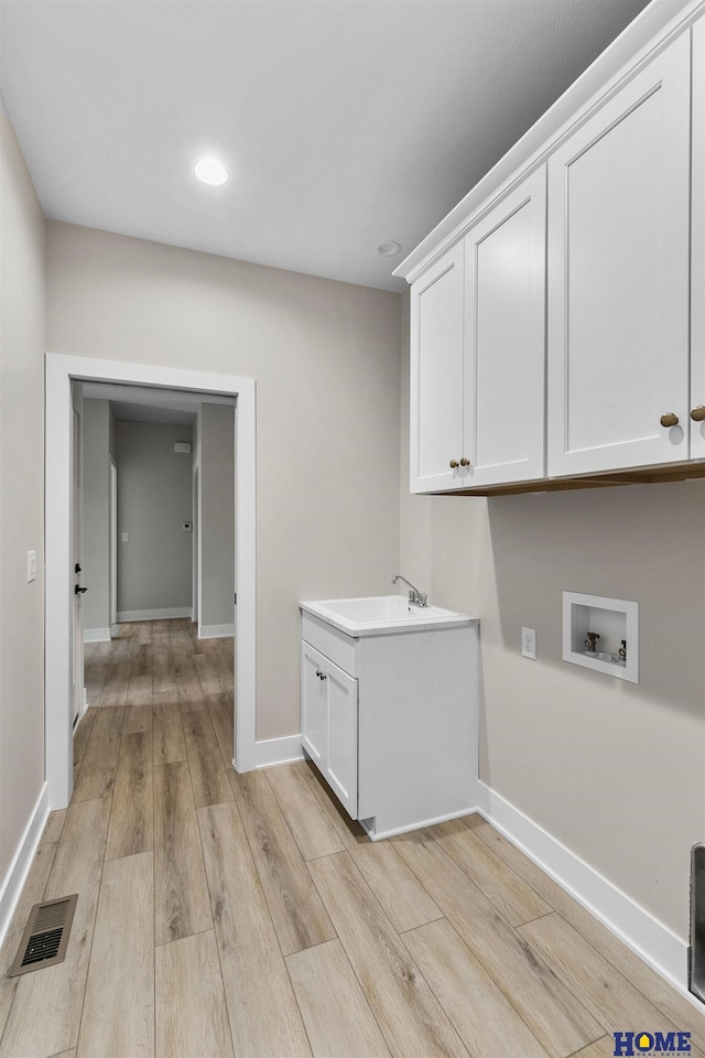 laundry area featuring sink, light hardwood / wood-style flooring, cabinets, and washer hookup