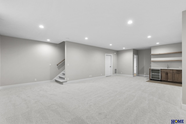 unfurnished living room with wet bar, light colored carpet, and wine cooler