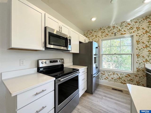 kitchen featuring white cabinets, light hardwood / wood-style floors, and appliances with stainless steel finishes