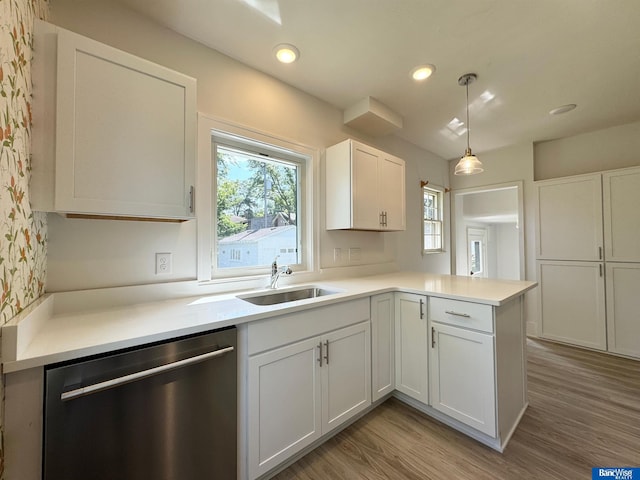 kitchen with dishwasher, kitchen peninsula, sink, decorative light fixtures, and white cabinetry