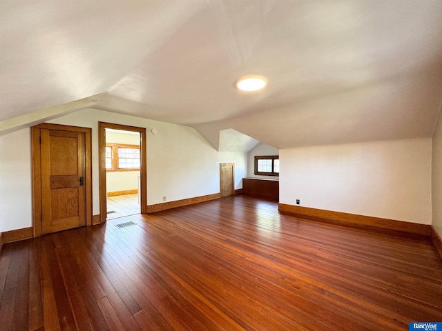 bonus room with dark wood-type flooring and vaulted ceiling