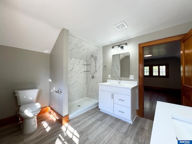 bathroom with vanity, tiled shower, hardwood / wood-style flooring, toilet, and lofted ceiling