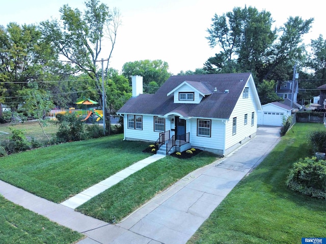 view of front of home featuring a garage, a playground, an outbuilding, and a front lawn