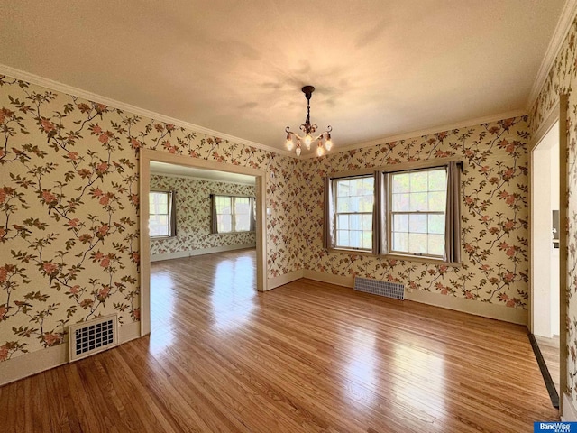 spare room with ornamental molding, a notable chandelier, and hardwood / wood-style flooring