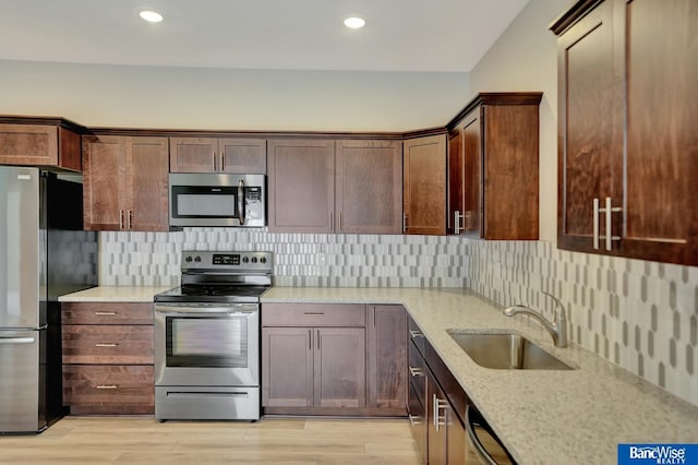 kitchen with sink, light stone countertops, stainless steel appliances, and tasteful backsplash