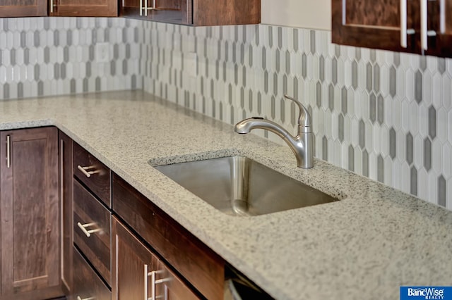 kitchen with tasteful backsplash, light stone counters, and sink