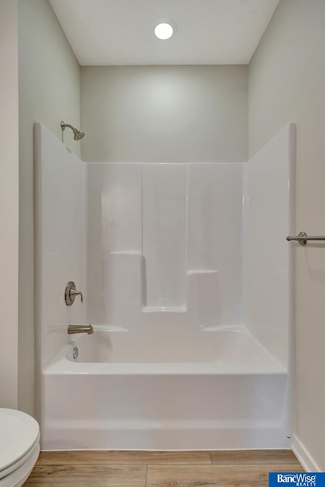 bathroom with bathing tub / shower combination, toilet, and hardwood / wood-style flooring