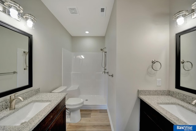 bathroom featuring hardwood / wood-style floors, vanity, toilet, and walk in shower