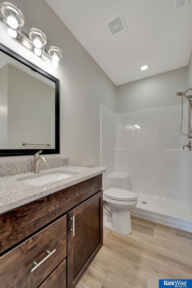 bathroom featuring walk in shower, hardwood / wood-style floors, vanity, and toilet