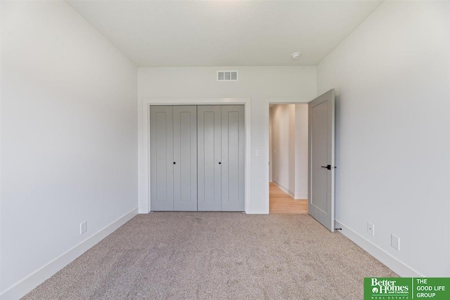 unfurnished bedroom with light carpet and a closet