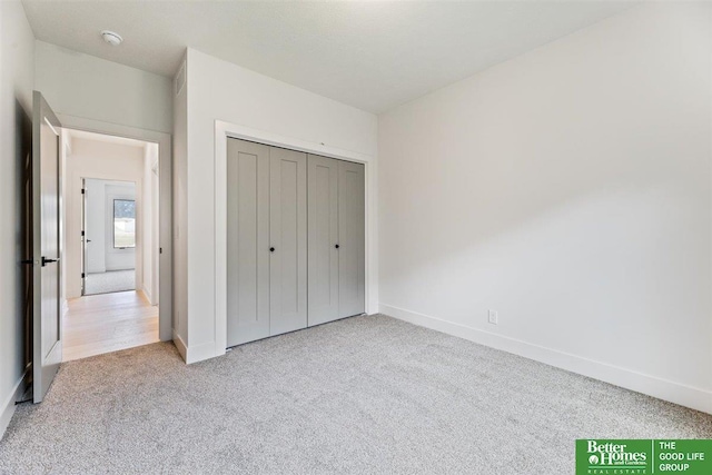 unfurnished bedroom featuring light carpet and a closet