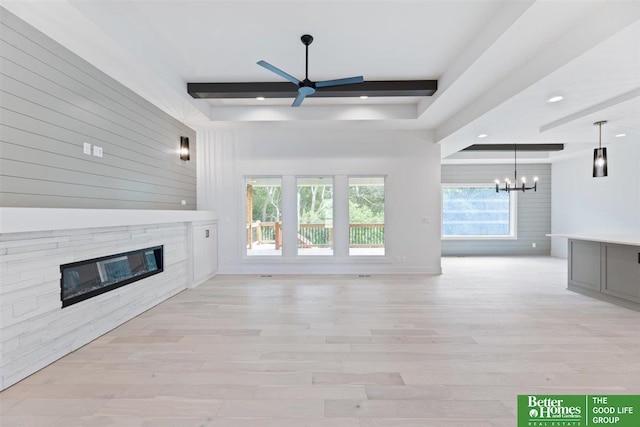 unfurnished living room featuring ceiling fan with notable chandelier, beam ceiling, and light hardwood / wood-style floors