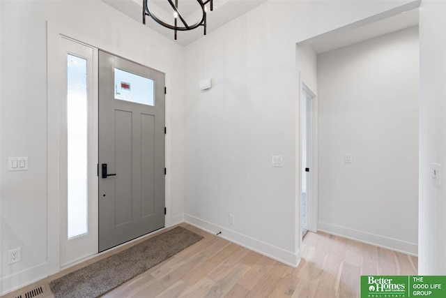 foyer with light hardwood / wood-style floors and an inviting chandelier