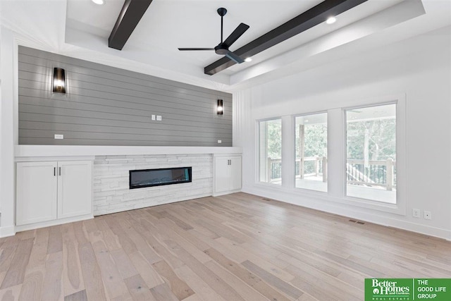 unfurnished living room with beam ceiling, light hardwood / wood-style floors, ceiling fan, and a tray ceiling