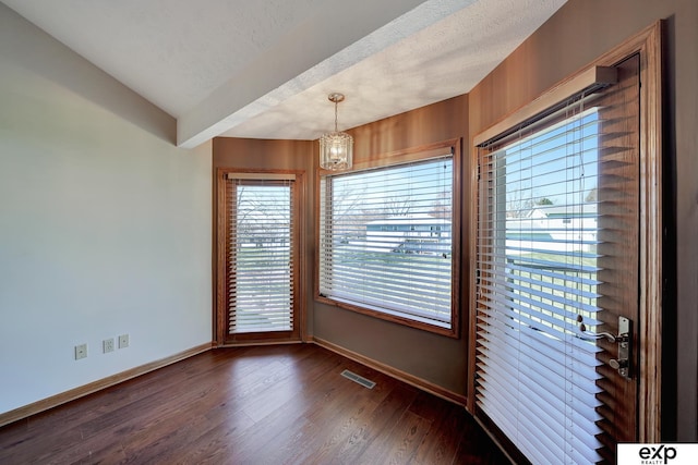 unfurnished room featuring dark hardwood / wood-style flooring, a textured ceiling, lofted ceiling, and a notable chandelier