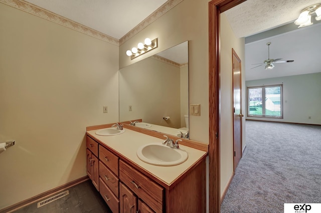 bathroom featuring ceiling fan, lofted ceiling, a textured ceiling, toilet, and vanity