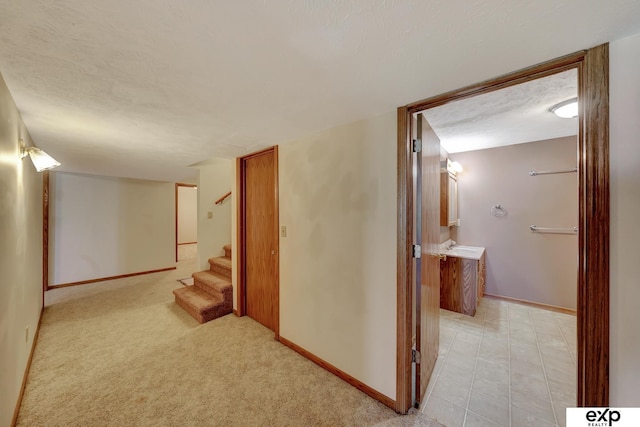 hallway with light carpet and a textured ceiling