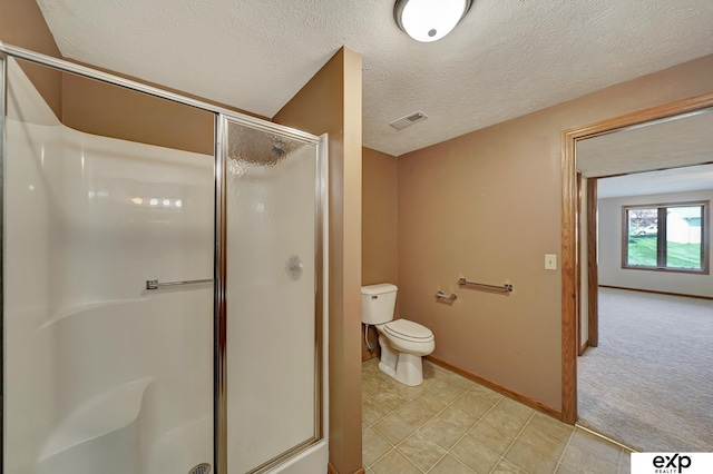 bathroom featuring toilet, a shower with shower door, and a textured ceiling