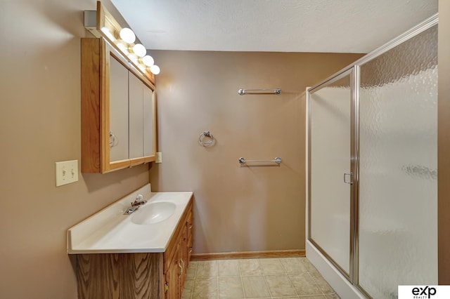 bathroom featuring vanity, a shower with shower door, and a textured ceiling