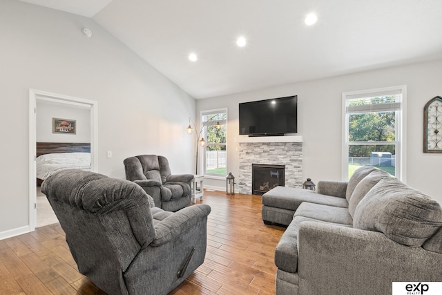 living room with a stone fireplace, lofted ceiling, and a wealth of natural light