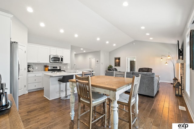 dining area with dark hardwood / wood-style floors, vaulted ceiling, and sink