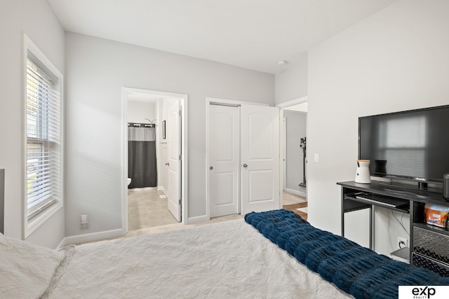 bedroom with ensuite bath, light carpet, and a closet