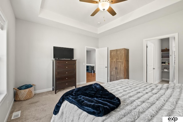 carpeted bedroom with ceiling fan and a raised ceiling