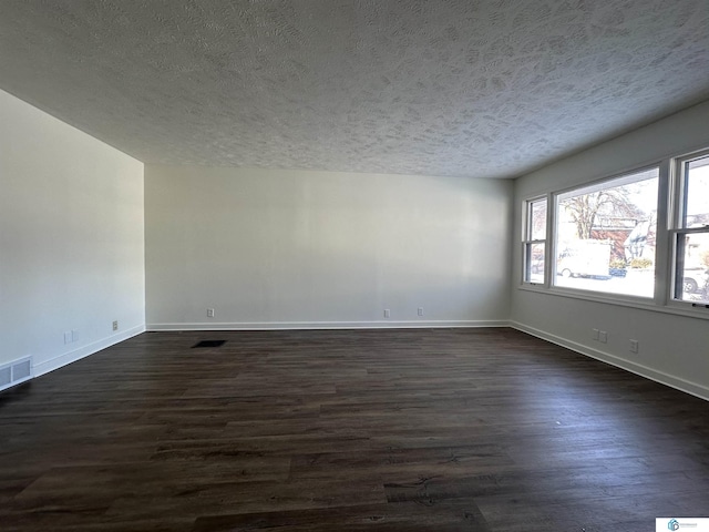 unfurnished room with a textured ceiling and dark wood-type flooring