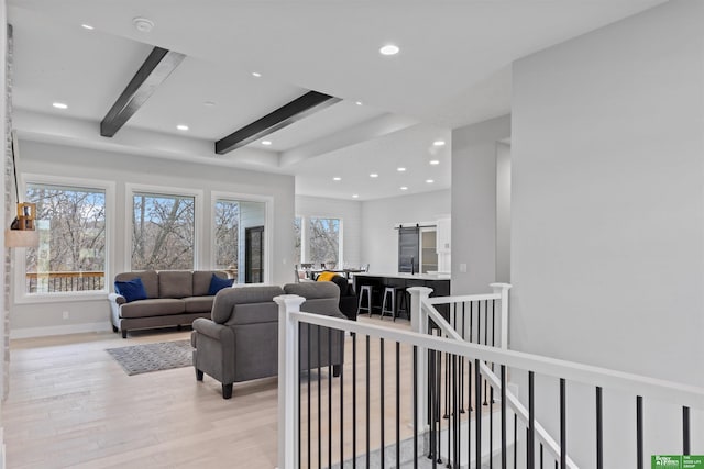 living room featuring beamed ceiling, light hardwood / wood-style floors, and sink