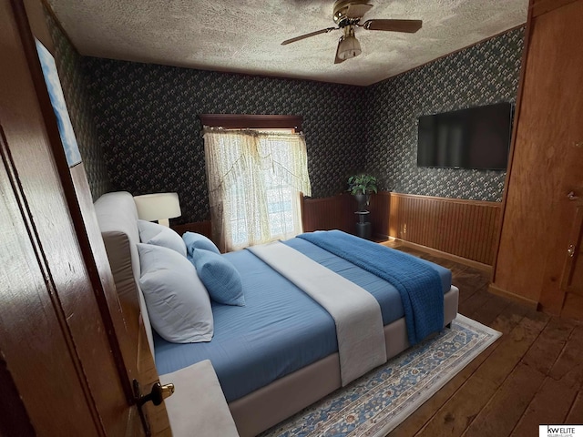 bedroom with ceiling fan, wood walls, and dark hardwood / wood-style floors