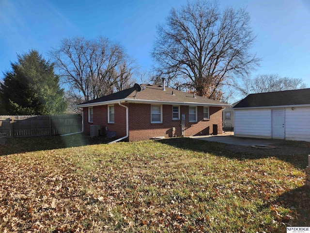 back of house with a lawn, an outbuilding, central air condition unit, and a patio