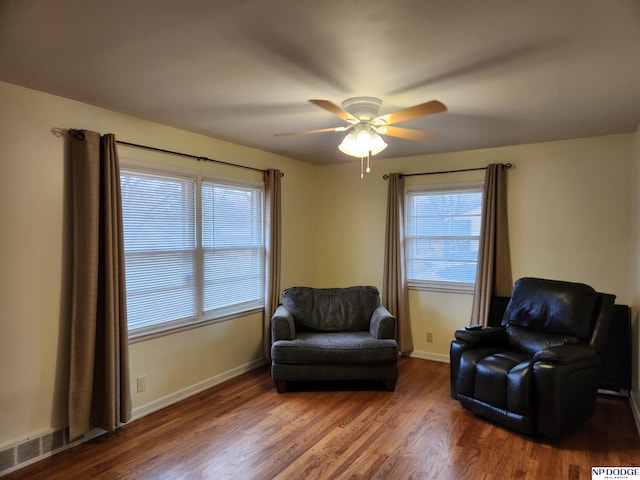 living area with ceiling fan, dark hardwood / wood-style floors, and a healthy amount of sunlight