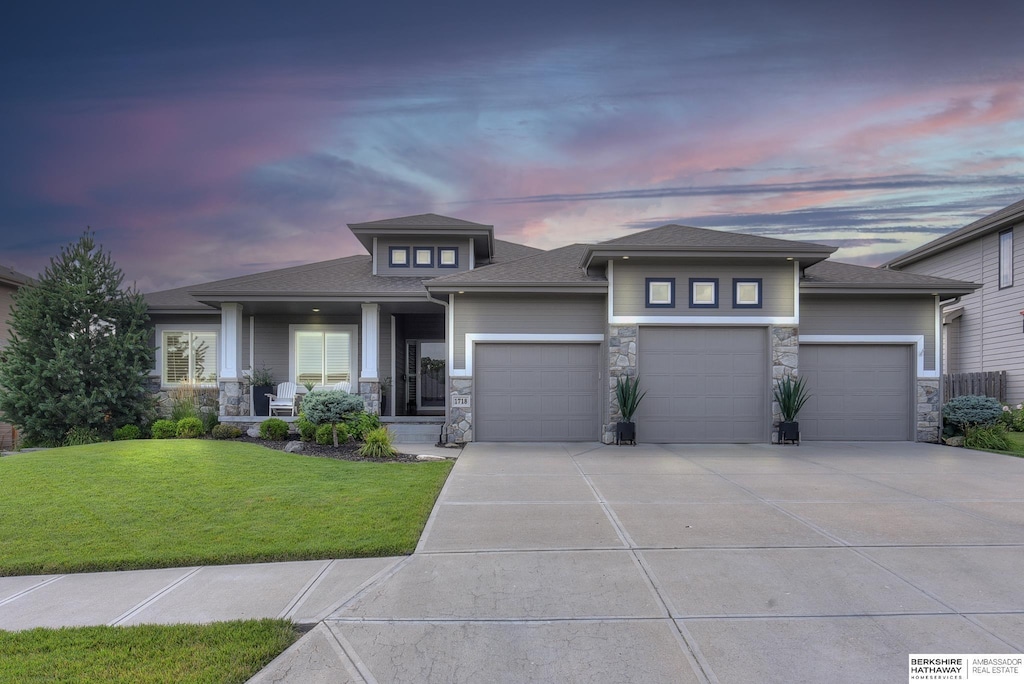 prairie-style home with a garage and a yard