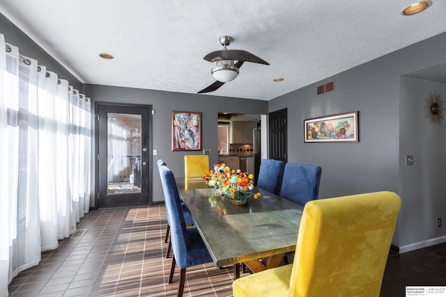 tiled dining area featuring ceiling fan and a textured ceiling